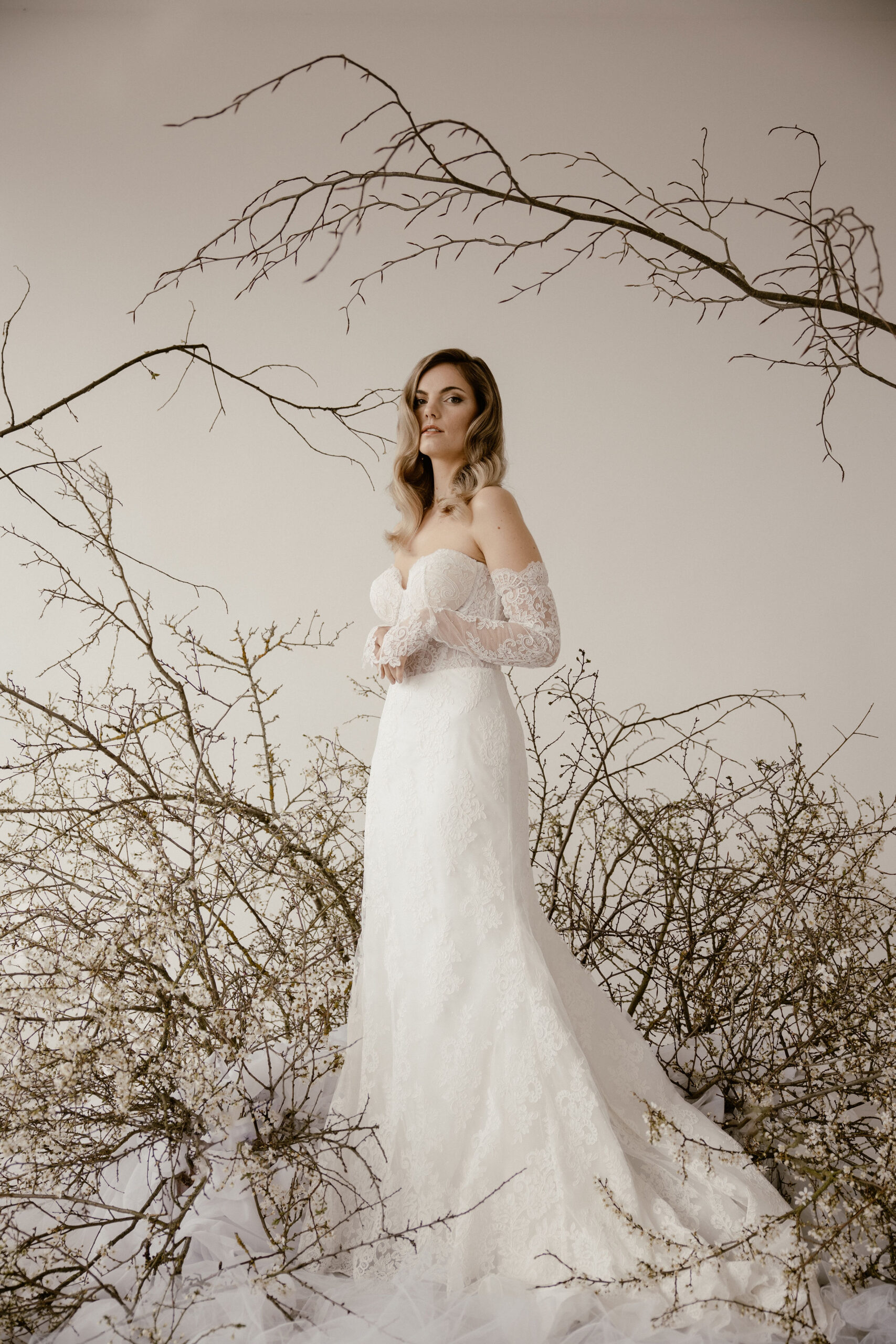 Braut mit offenen, sanft gewellten Haaren und elegantem Make-up im weißen Spitzenkleid
